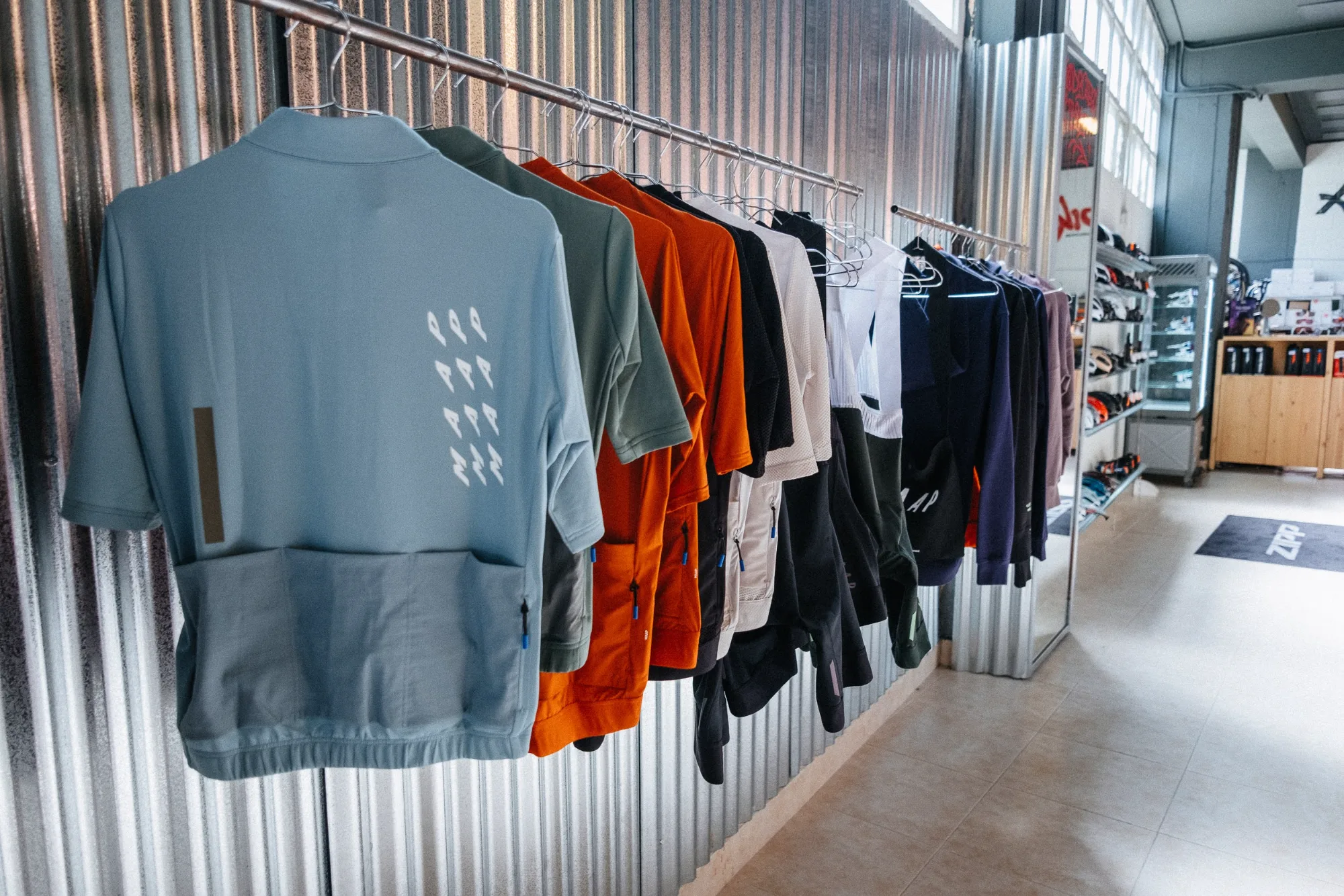 Cycling apparel hanging on metal clothes rail mounted against raw corrugated galvanized steel wall