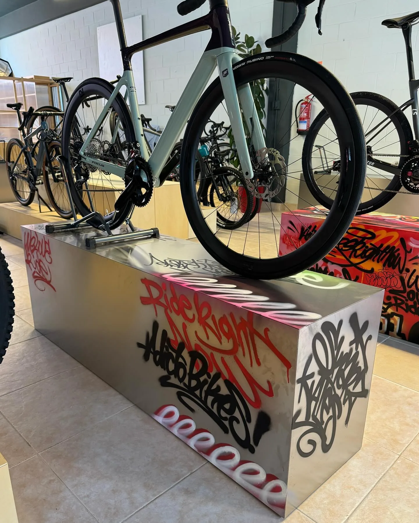 Road bicycle displayed on a metal podium covered in custom graffiti street art