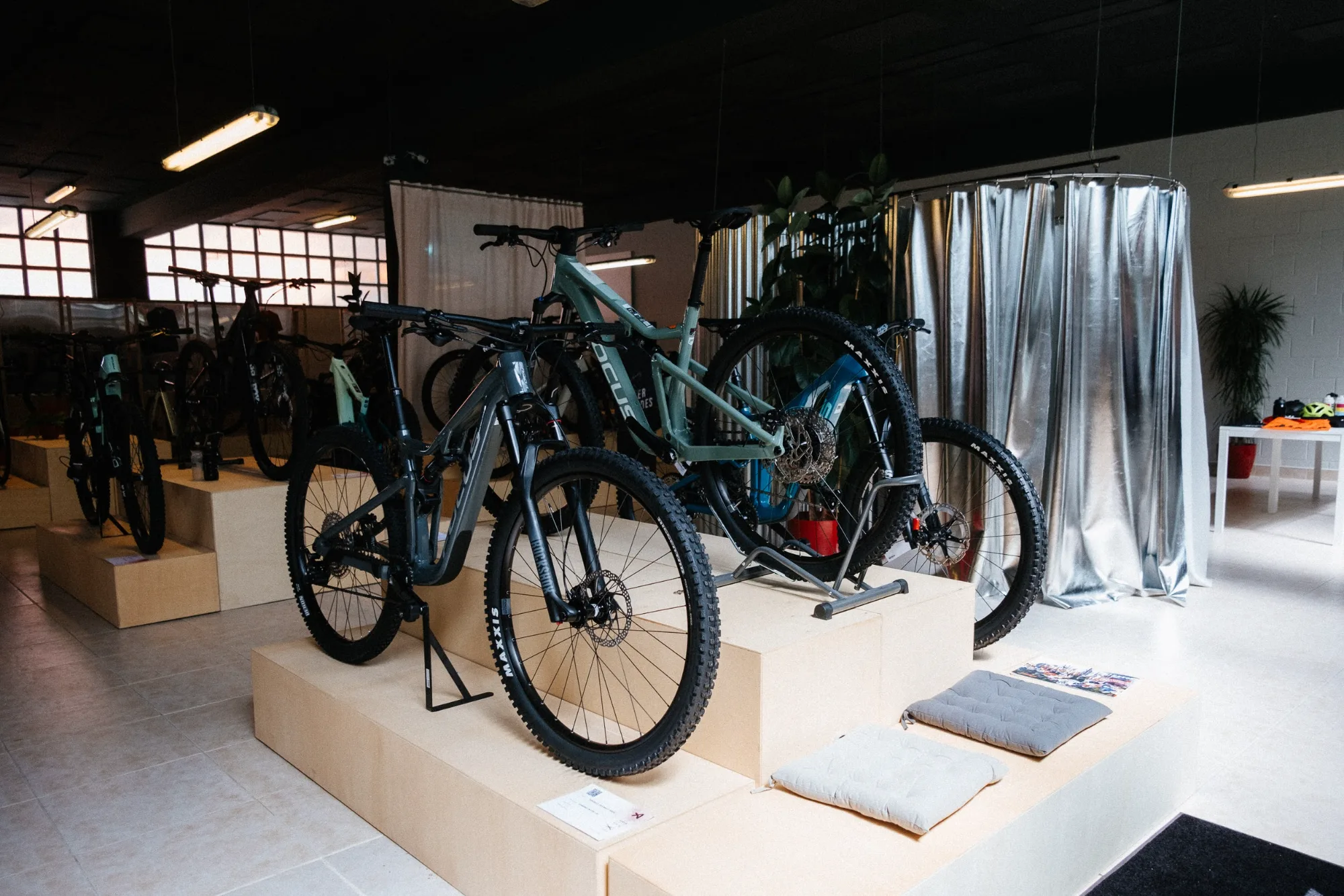 Mountain bicycles displayed on multi-tier modular plywood podiums with silver metallic curtain backdrop