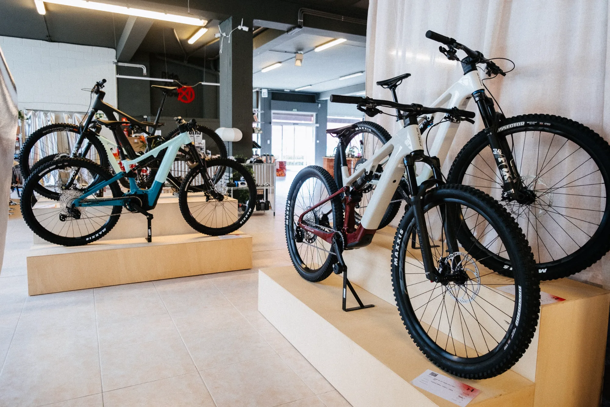 Mountain and gravel bicycles displayed on stepped wooden modular podiums in retail showroom