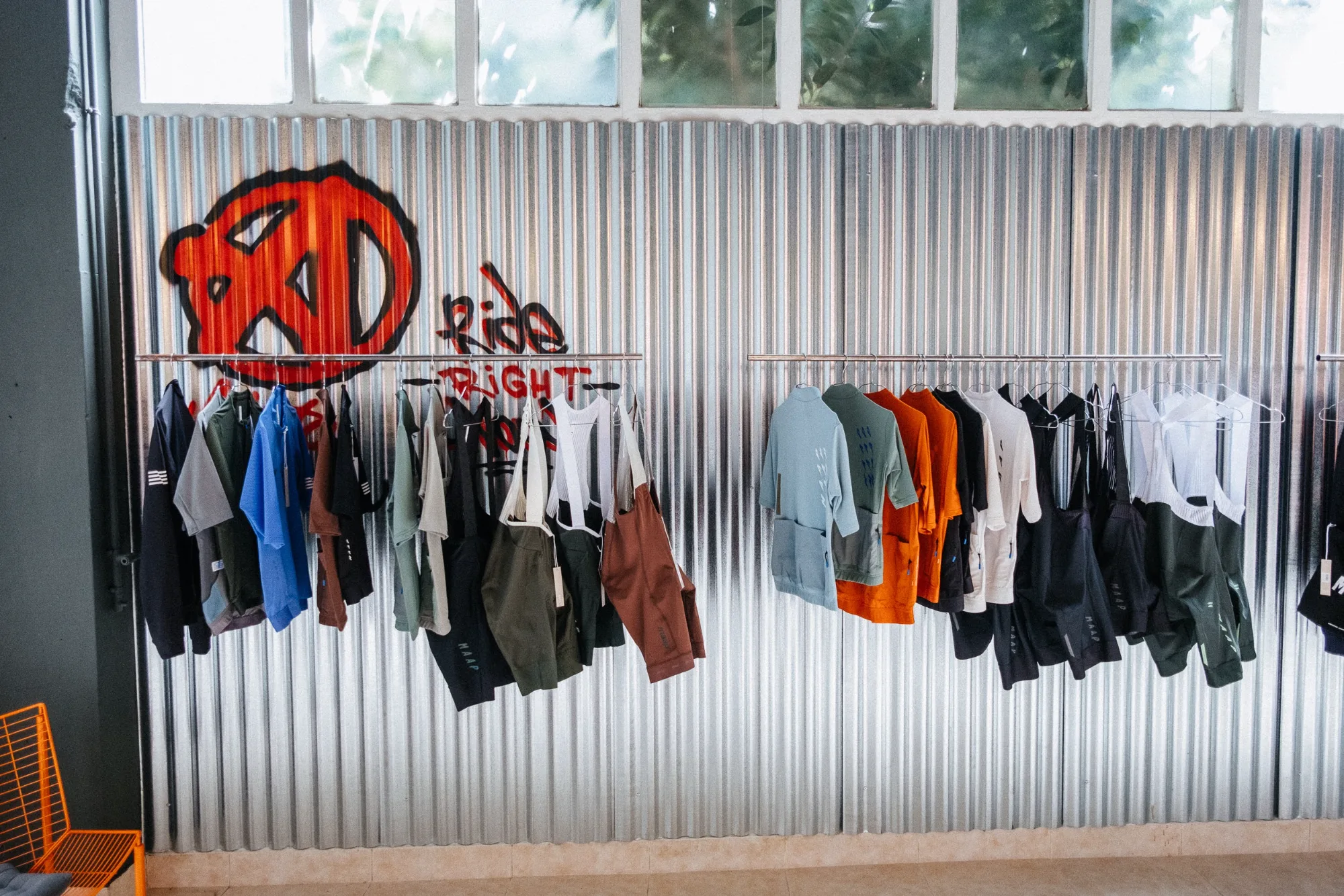 Corrugated galvanized steel wall with spray paint graffiti art and hanging cycling jerseys and bib shorts