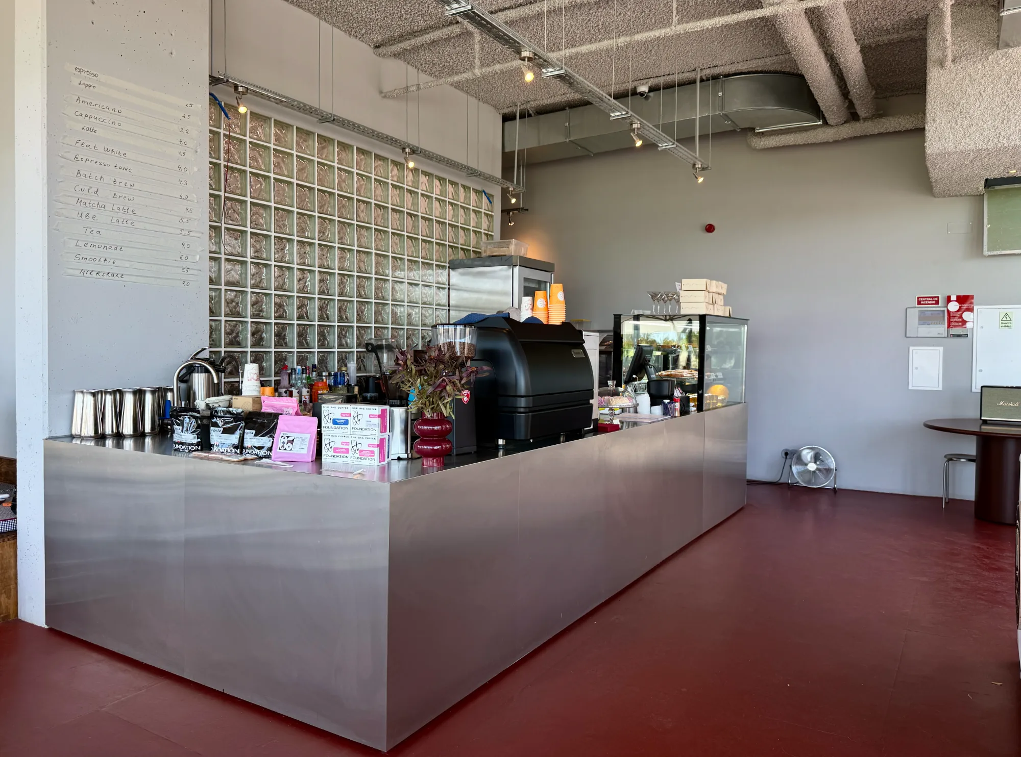 Monolithic stainless steel coffee bar counter with glass block wall partition and handwritten menu