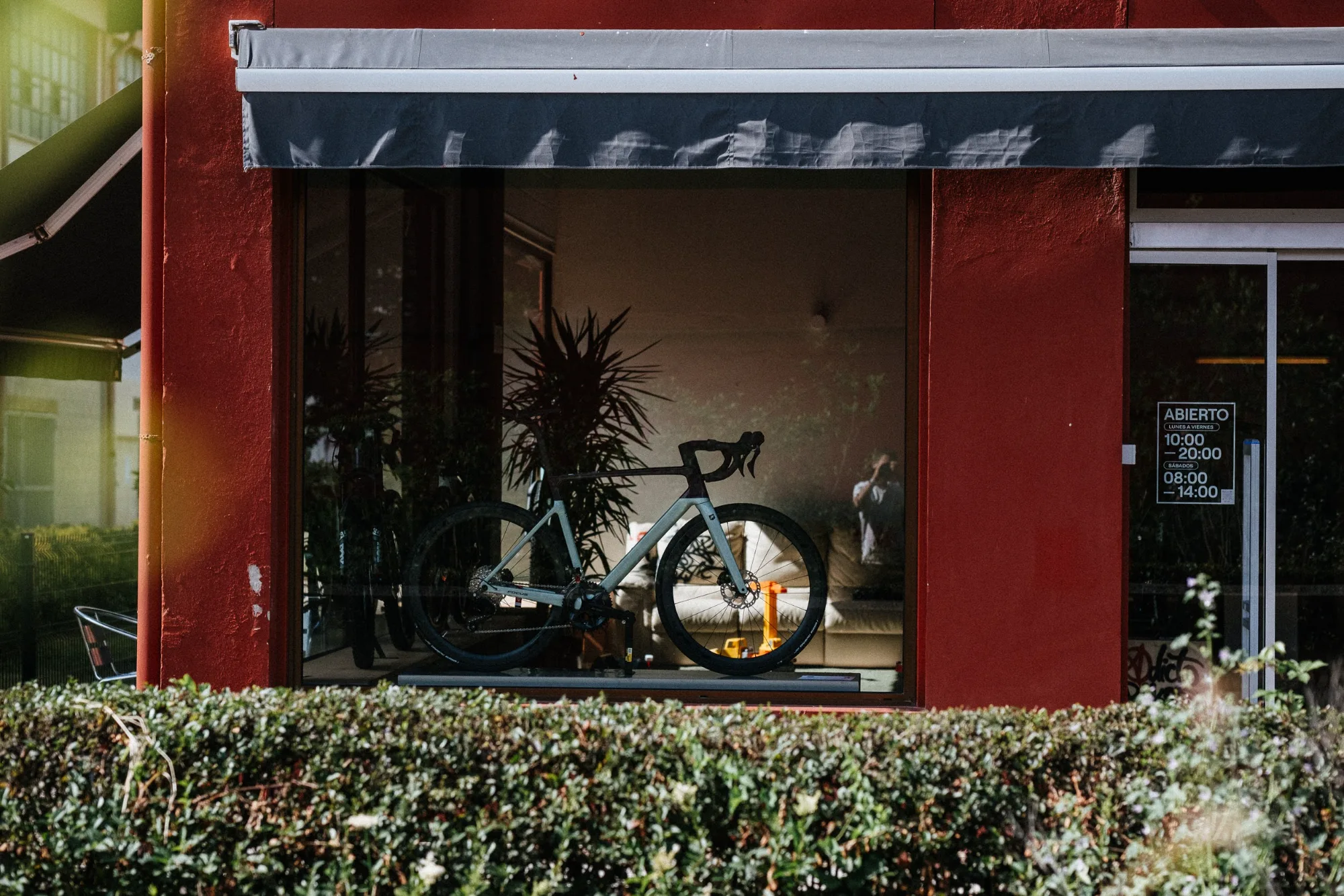 Storefront display window showing modern road bicycle on a platform inside a red brick building