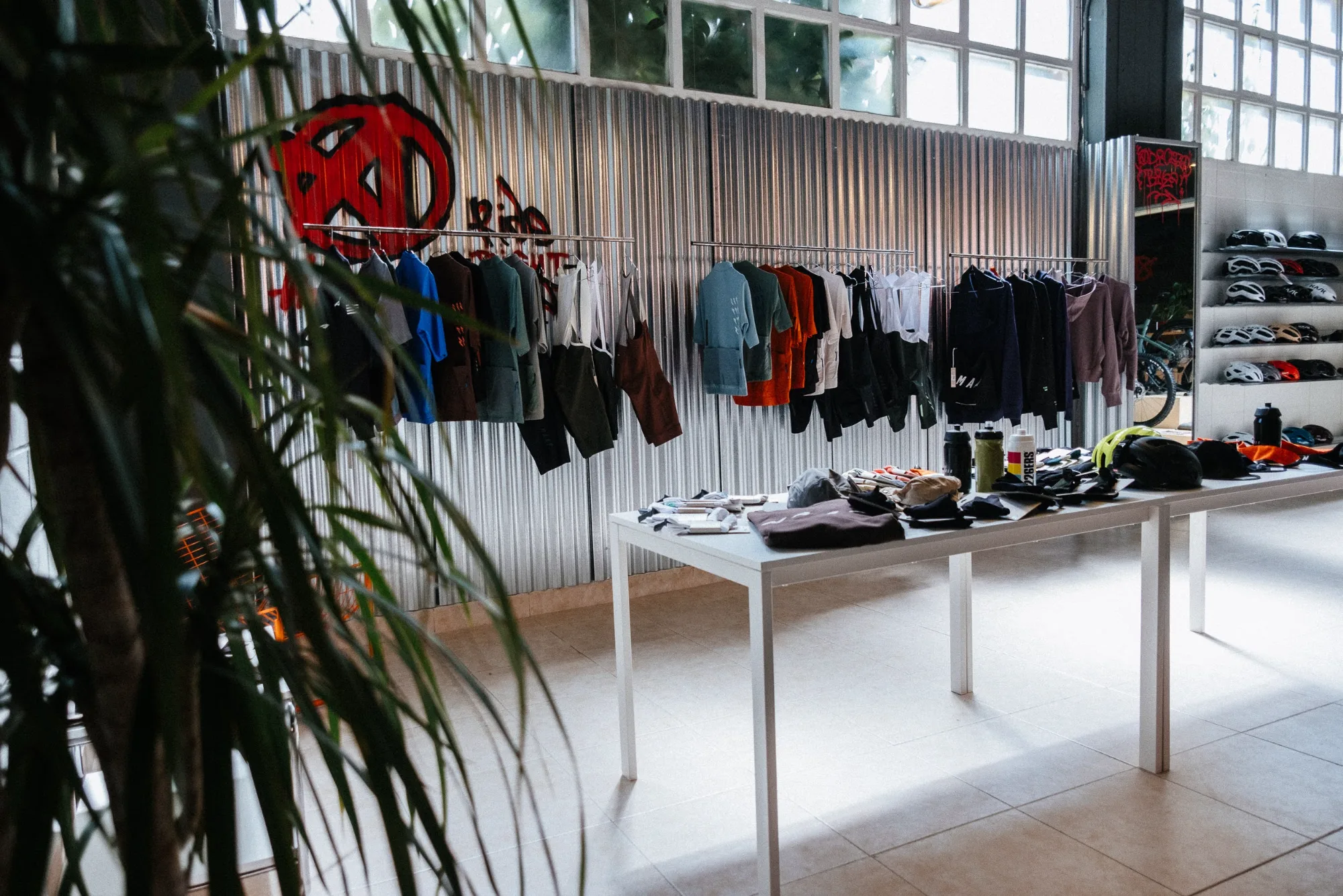 Retail store interior with display table, indoor plants, and corrugated galvanized steel wall with graffiti